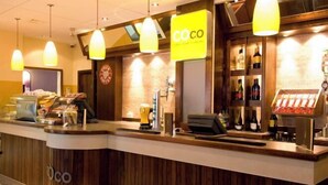 A hotel reception area with a wooden counter, a coffee machine, a cash register, and a wine display. - Coventry City Centre (Coventry)