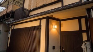 A traditional Japanese building with a wooden gate, a sliding door, and a lantern on the wall. - KIRAKU・SATOZAKURA (Kyoto)