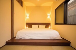 A single bed with a wooden headboard in a room with a small window and two wall-mounted lights. - KIRAKU・SATOZAKURA (Kyoto)