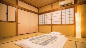 A traditional Japanese room with tatami flooring, a futon bed, sliding doors, and a large window with a view. - KIRAKU・SATOZAKURA (Kyoto)