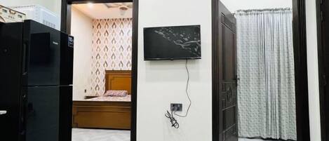 A room with a bed, a television mounted on the wall, and a door leading to another room.