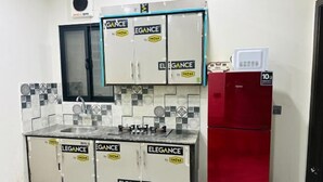 A compact kitchen with a sink, stove, and a red refrigerator. - Premium Apartments (Gujranwala)