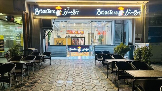An outdoor cafe with hexagonal patterned flooring, tables, and chairs. - Premium Apartments (Gujranwala)