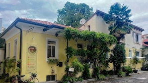 A yellow building with a red roof, potted plants, and a bicycle. - The Crystal Suite - Gorizia Central Apartment (Gorizia)