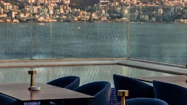 Un ristorante con vista sulla città, tavoli e sedie e una ringhiera in vetro.