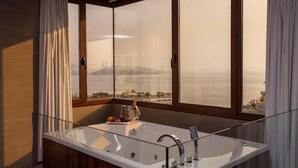 Un bagno moderno con una vasca da bagno ampia, una cabina doccia in vetro e vista sulla città attraverso grandi finestre.