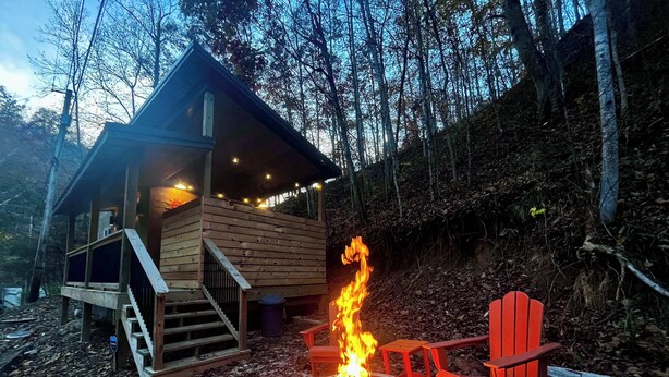 Eine Hütte mit Feuerstelle und einem roten Stuhl vor der Tür.