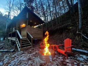 Una cabaña con un brasero y una silla roja en el exterior.