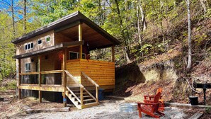 Eine Hütte mit einer Holzterrasse, einer Treppe und einem Stuhl.