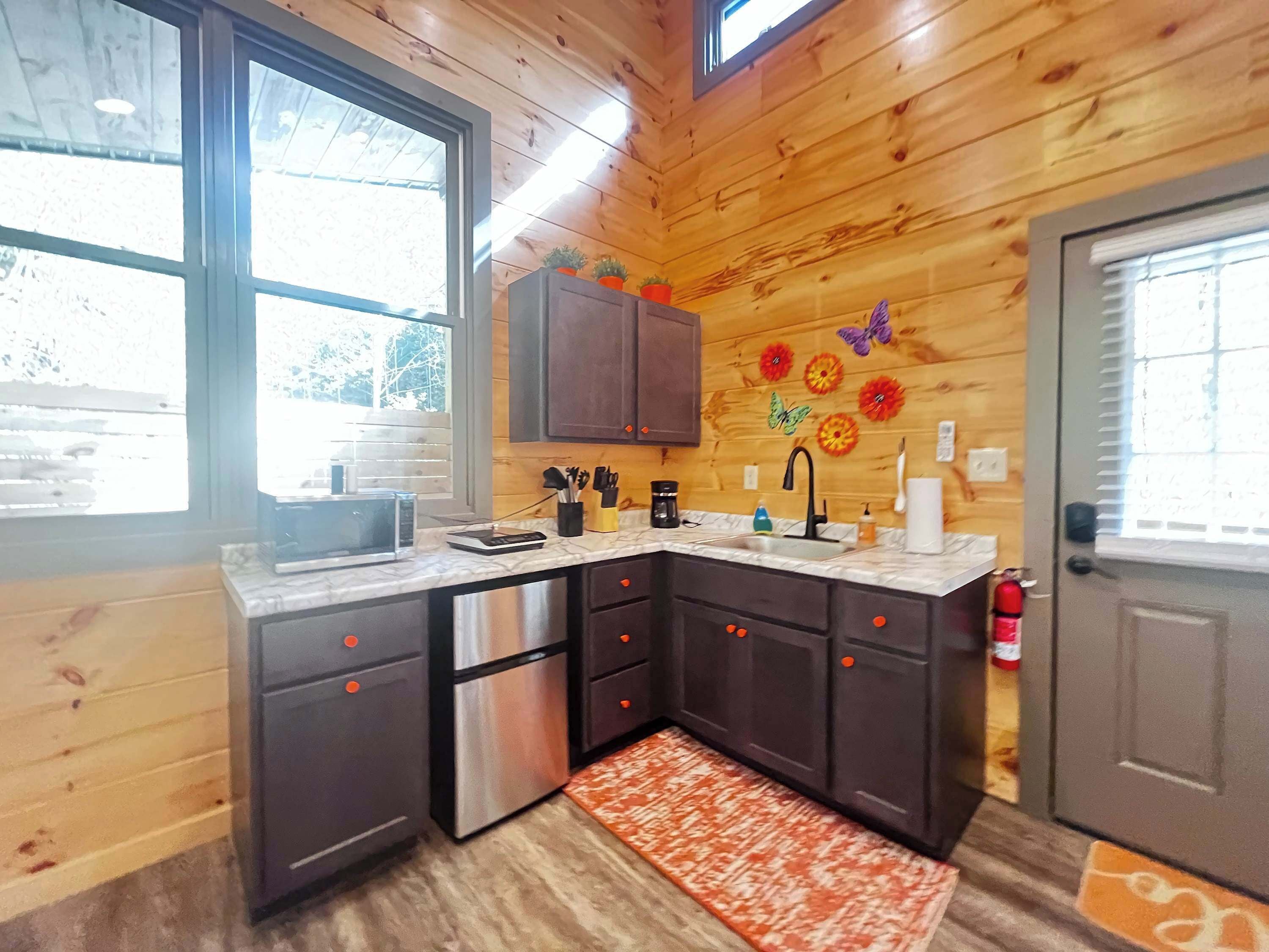 A kitchen with wooden walls, a stainless steel refrigerator, a sink, and cabinets.