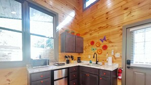 Eine Küche mit Holzwänden, einem Edelstahlkühlschrank, einer Spüle und Schränken.
