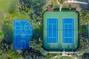 Dos canchas de tenis rodeadas de vegetación y senderos.