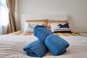 A bed with a striped bedspread, a folded blue towel, and pillows with text. - #GA2, Cozy 2R2B Relaxing Skyline Views (Shah Alam)