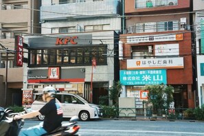 Une vue de rue avec un restaurant KFC, une enseigne indiquant un commerce et une voiture garée.