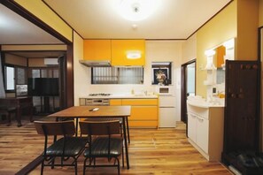 Une cuisine compacte avec un coin repas, un plancher en bois et un petit îlot central.