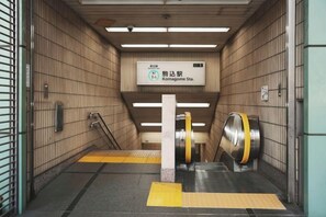 Een metrostation met een bord waarop Station Komagome staat aangegeven, een perron met geel voelbare tegels, en een treinopgang.