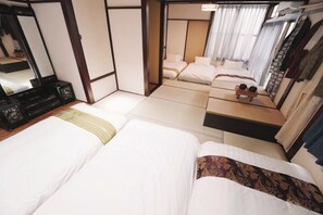 Een hotelkamer met twee bedden, een kaptafel, een spiegel en uitzicht op een traditionele Japanse kamer.