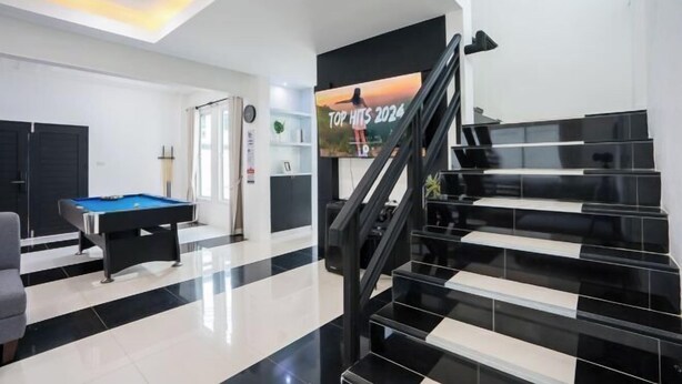 A modern indoor space with a pool table, a staircase, and a poster advertising 'TOP HITS 2024'. - White Chocolate Pool Villa (Bang Lamung)