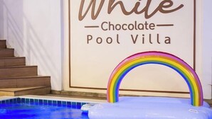 A swimming pool with a rainbow float and a sign reading "White Chocolate Pool Villa". - White Chocolate Pool Villa (Bang Lamung)