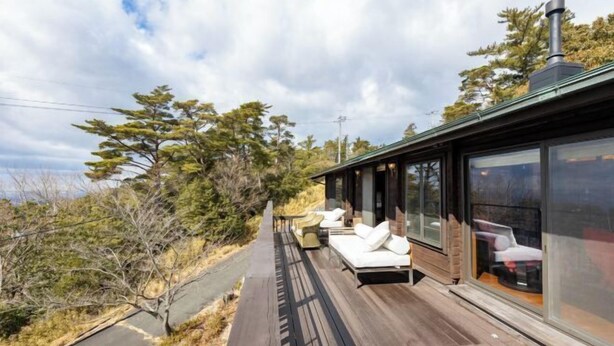 A modern building with a deck, outdoor seating, and large windows. - SHODOSHIMA PRIVATE CAMP SITE (Shodoshima)