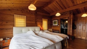 A log cabin bedroom with a large bed, wooden walls, and a ceiling with exposed beams. - SHODOSHIMA PRIVATE CAMP SITE (Shodoshima)