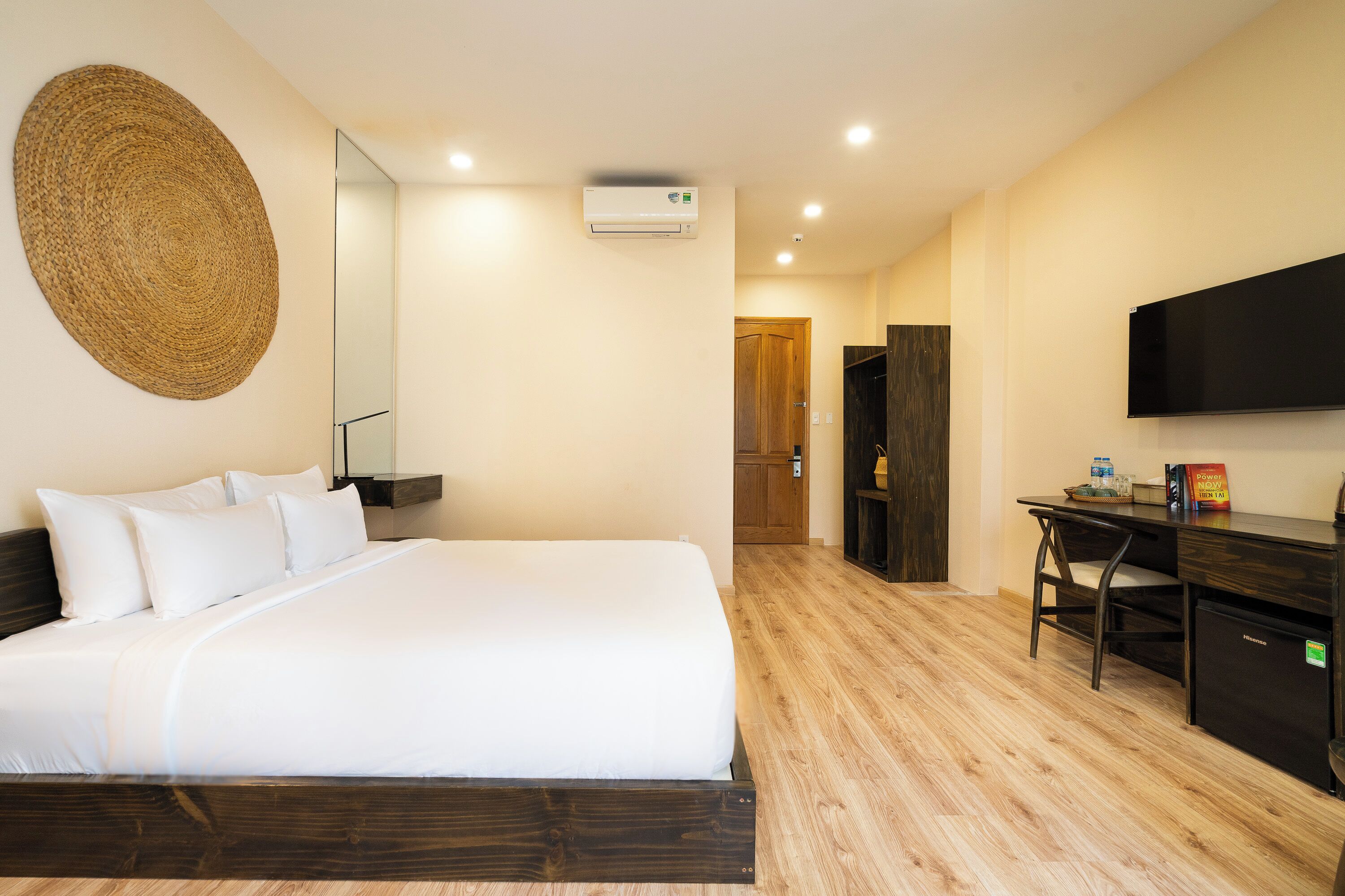 A hotel room with a bed, a desk, a chair, a television, and an air conditioning unit.