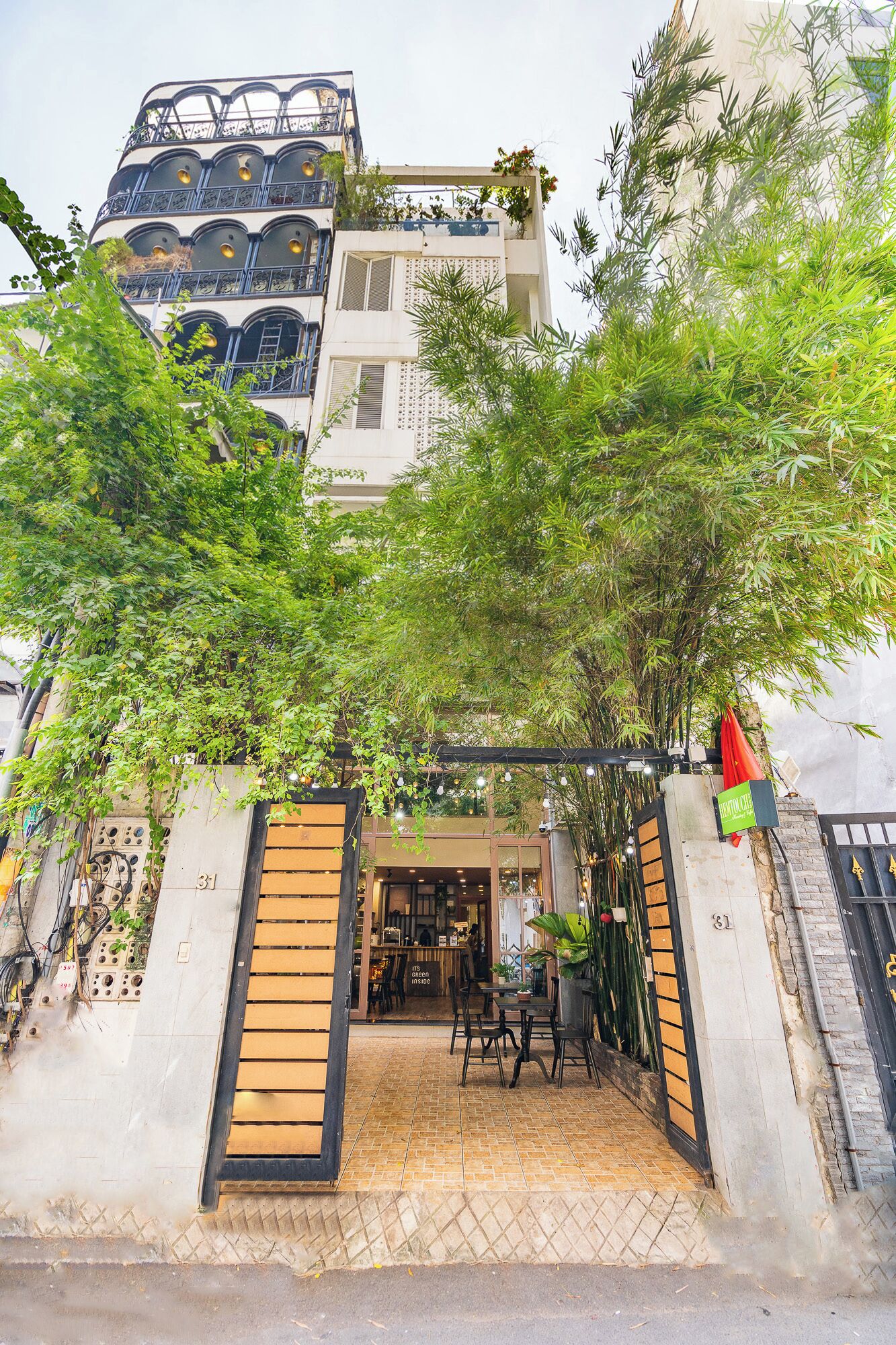 A building with a gated entrance, a small outdoor seating area, and a visible shop or cafe inside.
