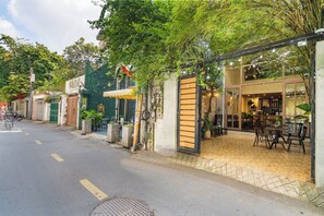 A street with outdoor seating, a green wall, and a building with a sign. - HemTouch House - Nguyen Van Mai (Xuan Hoa)