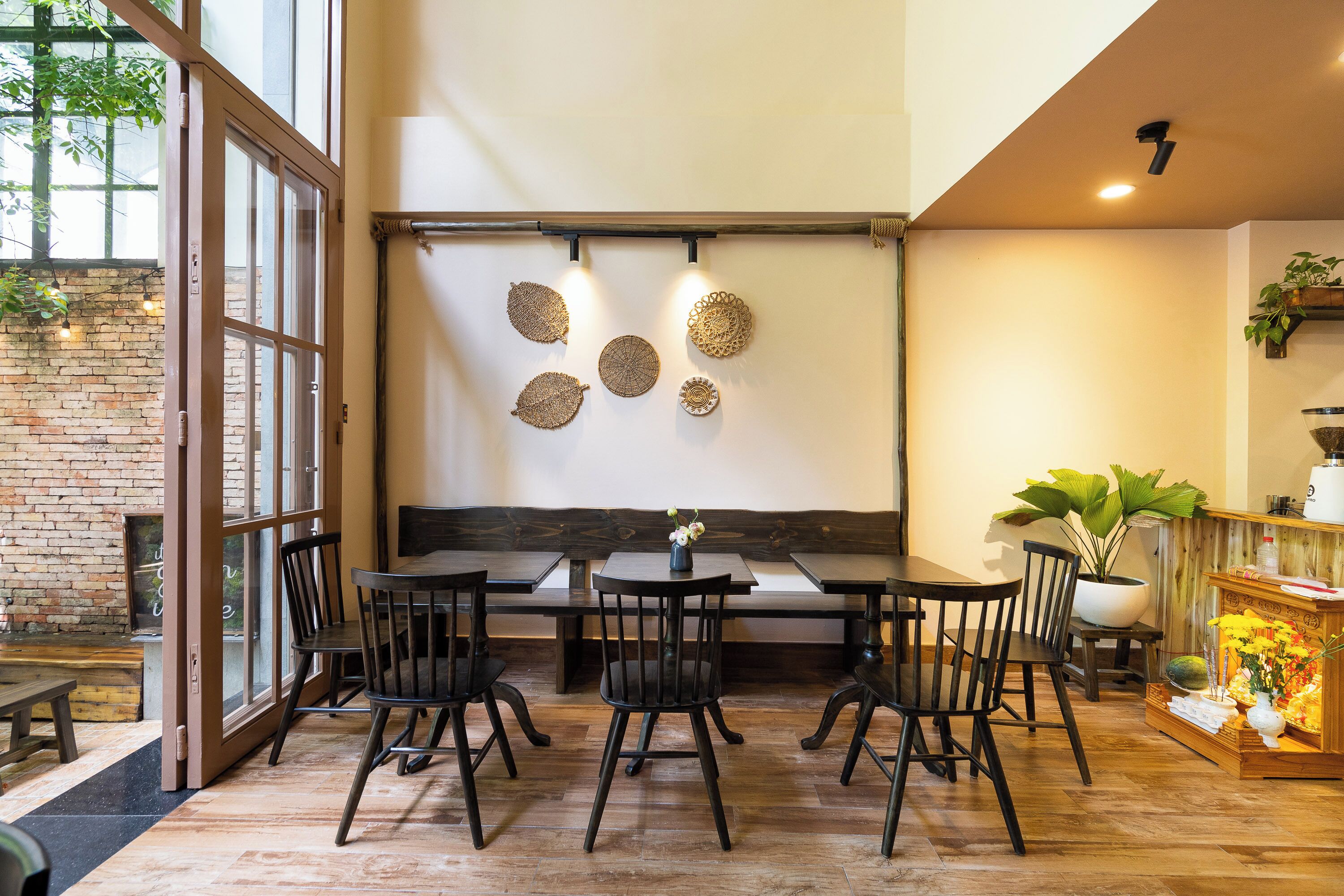 Un espace repas avec des tables et des chaises en bois, un banc et des œuvres d’art décoratives murales.
