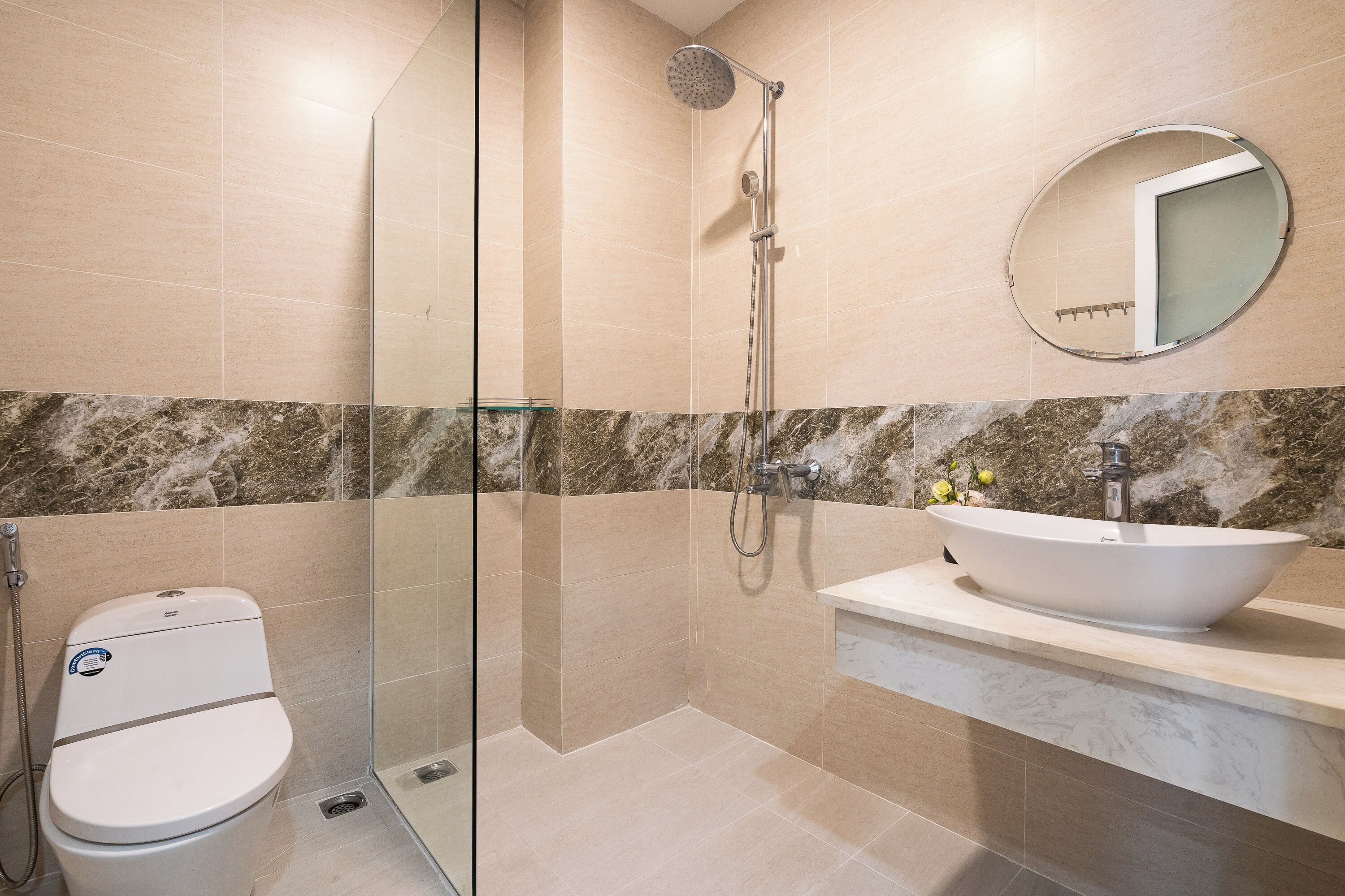 A modern bathroom with a glass-enclosed shower, a white sink, and a marble backsplash.