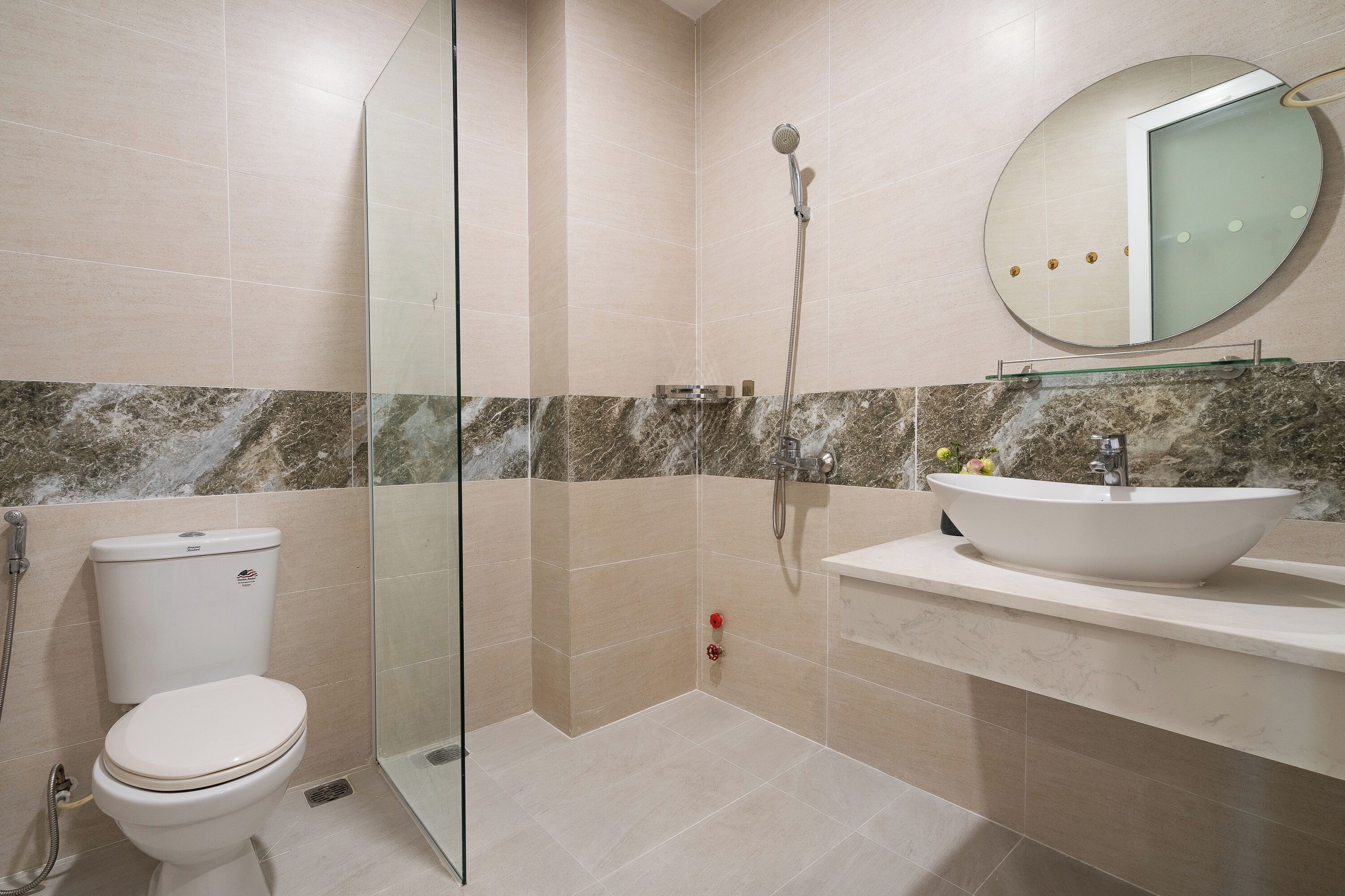 A bathroom with a toilet, a shower enclosure, a sink, and a mirror.