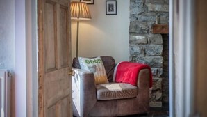 Una habitación acogedora con un sofá de cuero marrón, una lámpara y una pared de piedra.
