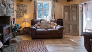 Una sala de estar acogedora con chimenea de piedra, sofá de cuero y puerta de madera.