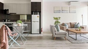 Una cocina moderna con refrigerador, estufa y comedor con mesa y sillas.