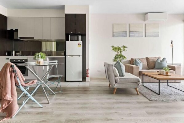 Eine moderne Küche mit Kühlschrank, Herd und Essbereich mit Tisch und Stühlen.