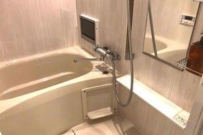 A bathroom with a bathtub, a handheld showerhead, a digital control panel, and a mirror. - Kinshicho 1001 (Tokyo)