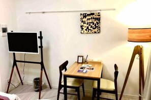 A room with a whiteboard on a stand, a table with chairs, a lamp, and a framed picture. - Kinshicho 1001 (Tokyo)