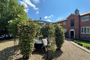 A garden with a gazebo, a building with a brick facade, and a gravel path. - Huntershields (Northampton)