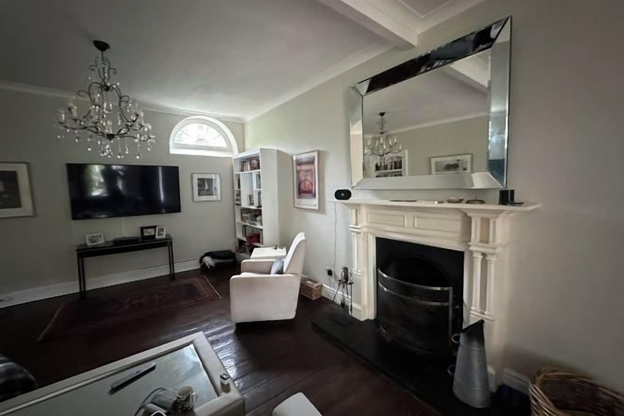 A living room with a fireplace, a television, and a chandelier.