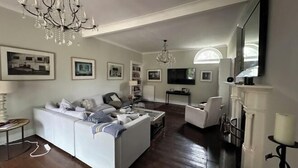A spacious living room with a white sofa, a chandelier, and a fireplace. - Huntershields (Northampton)