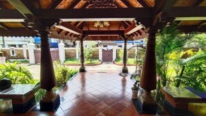 A covered outdoor area with tiled flooring, columns, and potted plants. - Azza Heritage Home (Kochi)