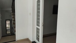 A hallway with a white door, a staircase, and a wall-mounted television. - Azza Heritage Home (Kochi)
