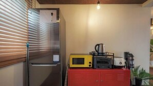 A compact kitchen with a stainless steel refrigerator, a microwave, a toaster, and a coffee maker on a red cabinet. - Hongdae Hanok (Seoul)