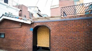 A brick building with a covered entrance and a small balcony. - Hongdae Hanok (Seoul)