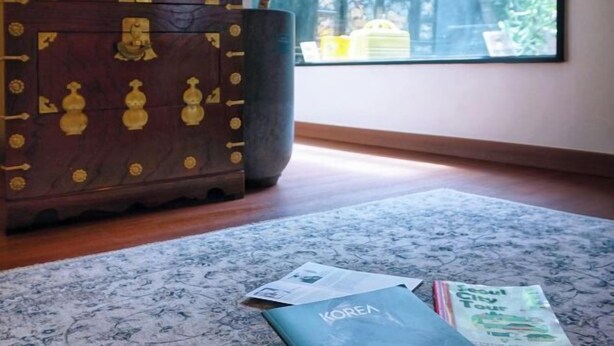 A room with a patterned rug, a wooden chest, and a window with a view of greenery. - Hongdae Hanok (Seoul)