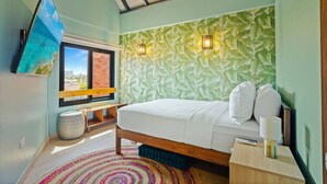 Une chambre à coucher avec un lit, une télévision, une fenêtre donnant sur un beau paysage et un mur à motifs.