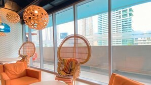 Un interior moderno con ventanas amplias, asientos naranja e iluminación decorativa.