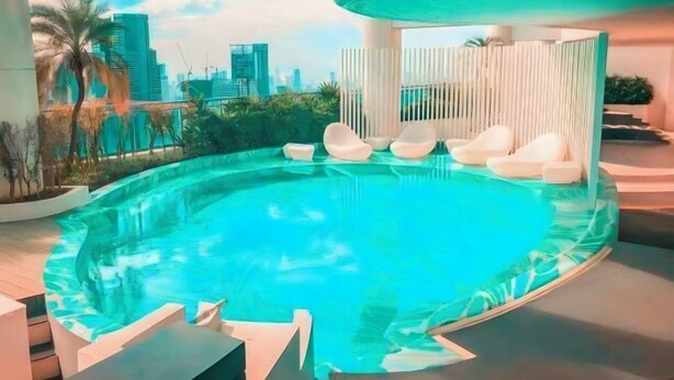 Una piscina interior moderna con vistas a la ciudad, rodeada de sillas reclinables blancas y un diseño minimalista.