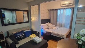 Una habitación de hotel moderna con cama, sofá, una mesita y un espejo.