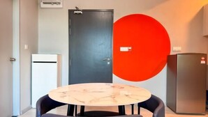 A room with a round table and two chairs, a black door, a red wall feature, and a refrigerator. - JQ Central 4 person unit facing mountain view and partially seaview AT kk CITY CENTER (Kota Kinabalu)